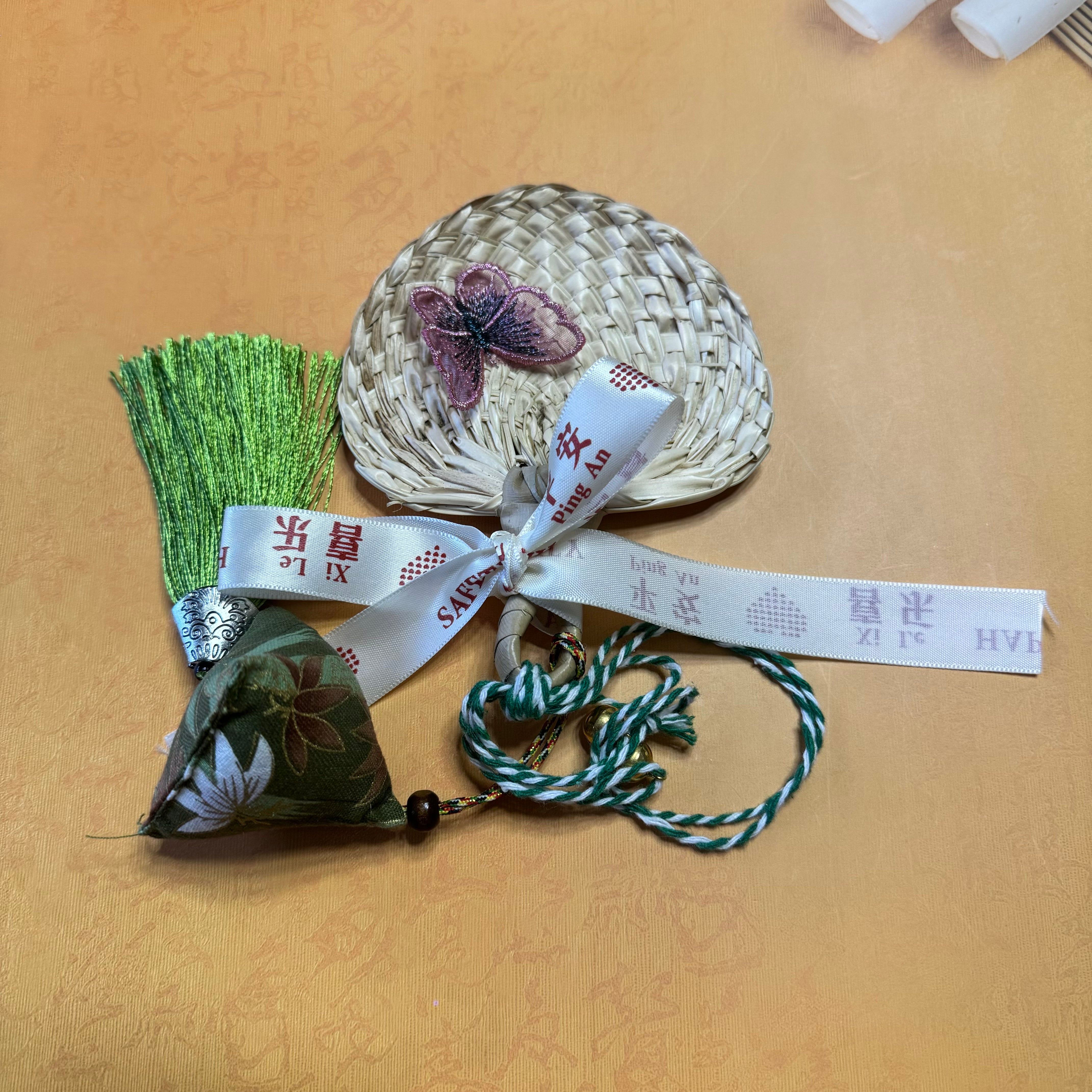 A palm leaf fan with a butterfly on top of the fan and a zongzi shape chain