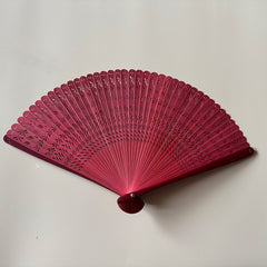 A red touqing bamboo fan on a white surface