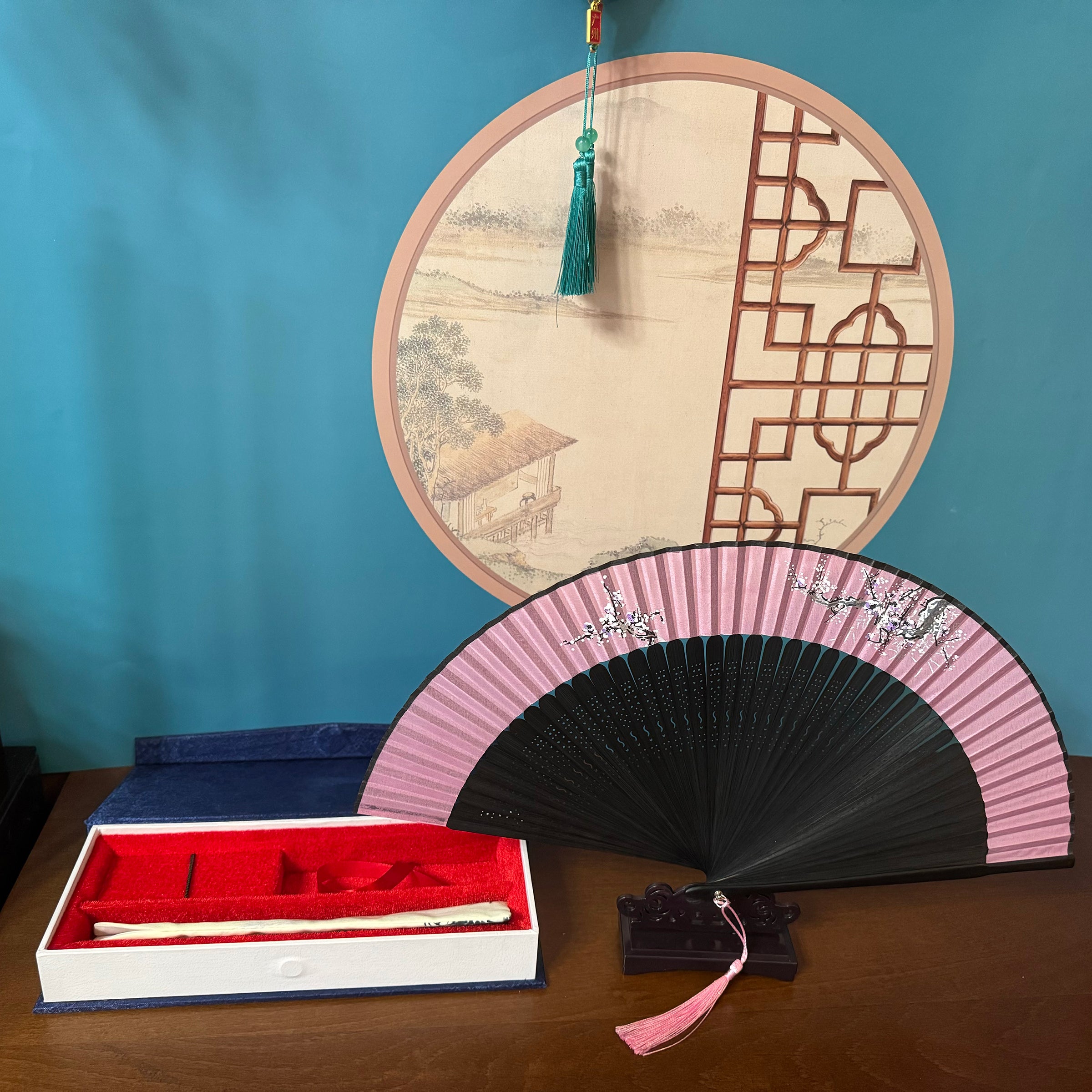 a dark blue box with surface patterns, containing a fan pouch, a fan placed on a fan stand beside it.