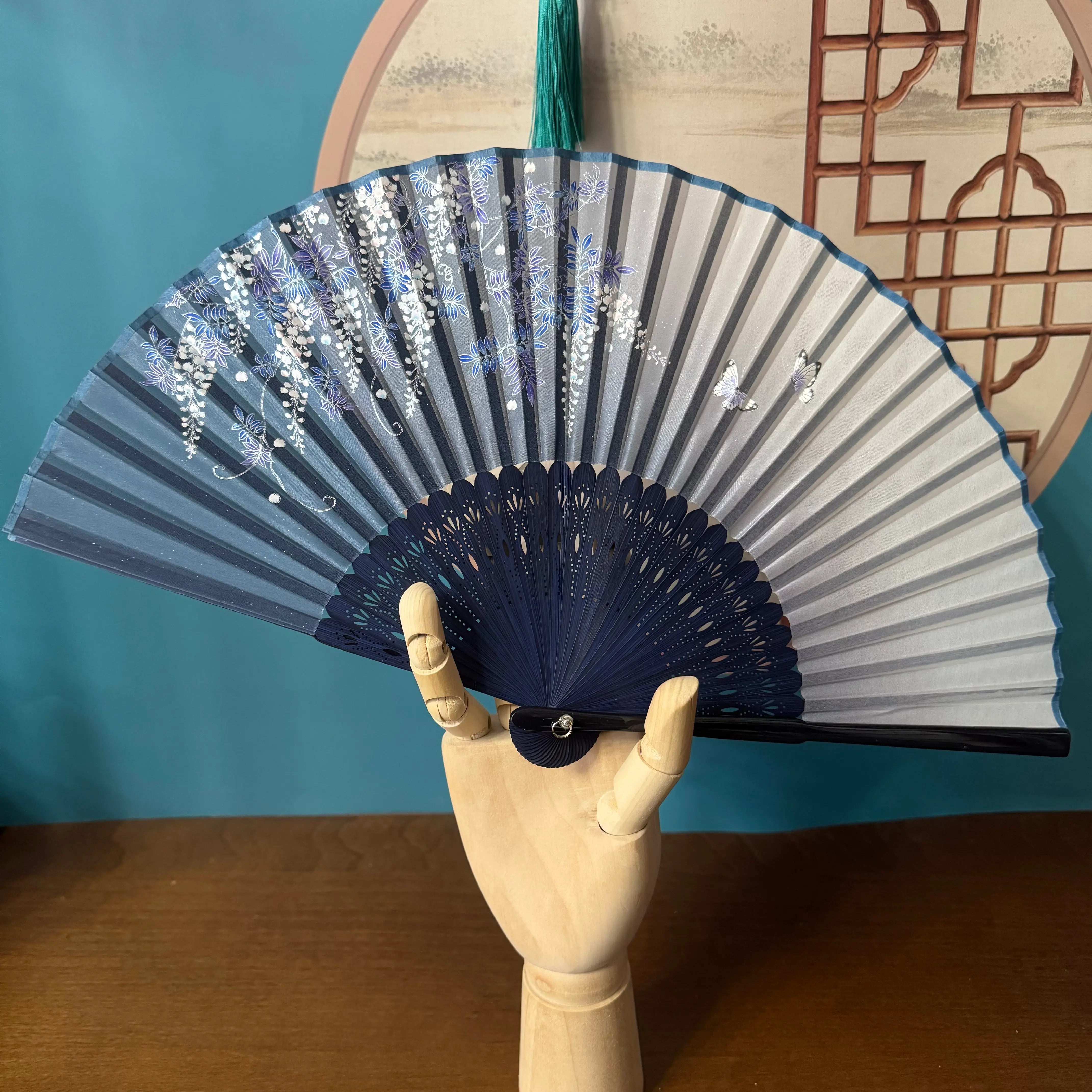 A wooden hand holding a Chinese bamboo folding fan