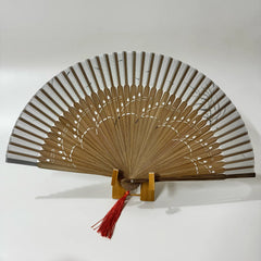 The back side of a pomegranate flower carved bamboo folding fan with a red tassel.