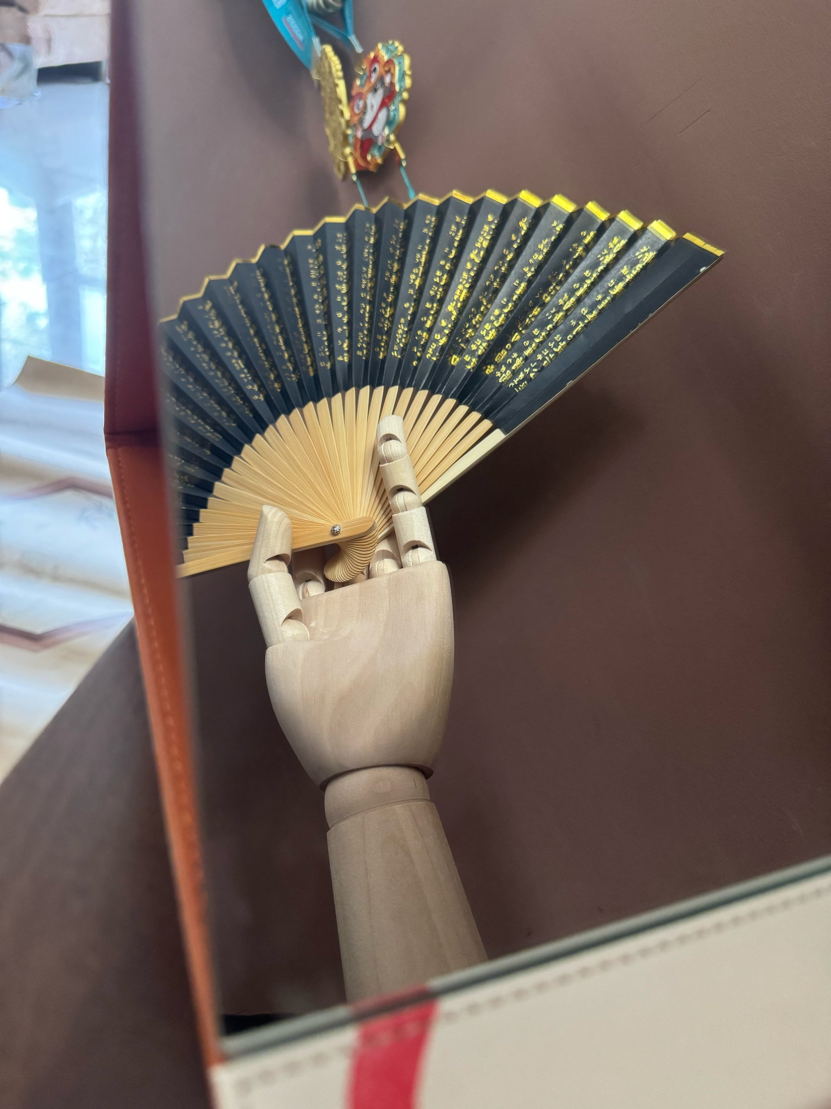 The reflection in the mirror shows a wooden hand holding a zen heart sutra fan