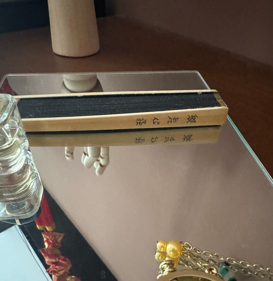 A folded Zen heart sutra fan placed on a mirror