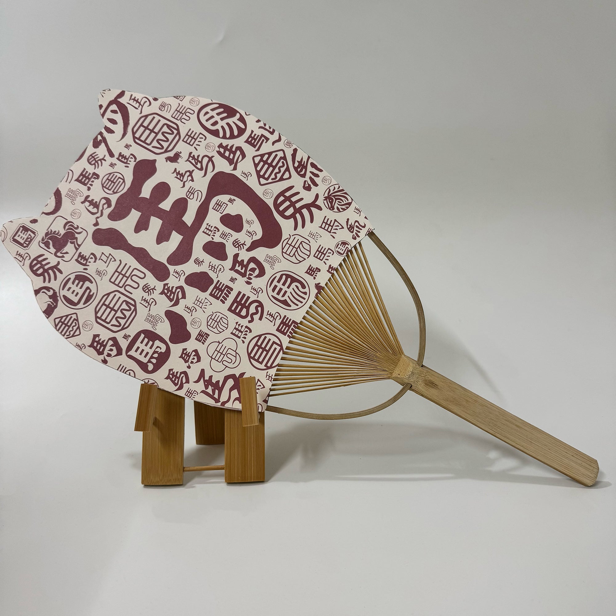 A Japanese round fan (uchiwa fan) with cat ears. On the fan panel it prints Chinese characters says horse.