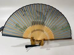 The back side of a Chinese silk phoenix folding fan is displayed on a fan stand.
