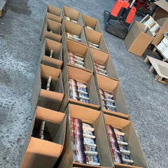 Custom printed promotional hand fans from a factory order. Fifteen packed but unsealed boxes of fans are shown on the factory floor, awaiting sealing before shipment.