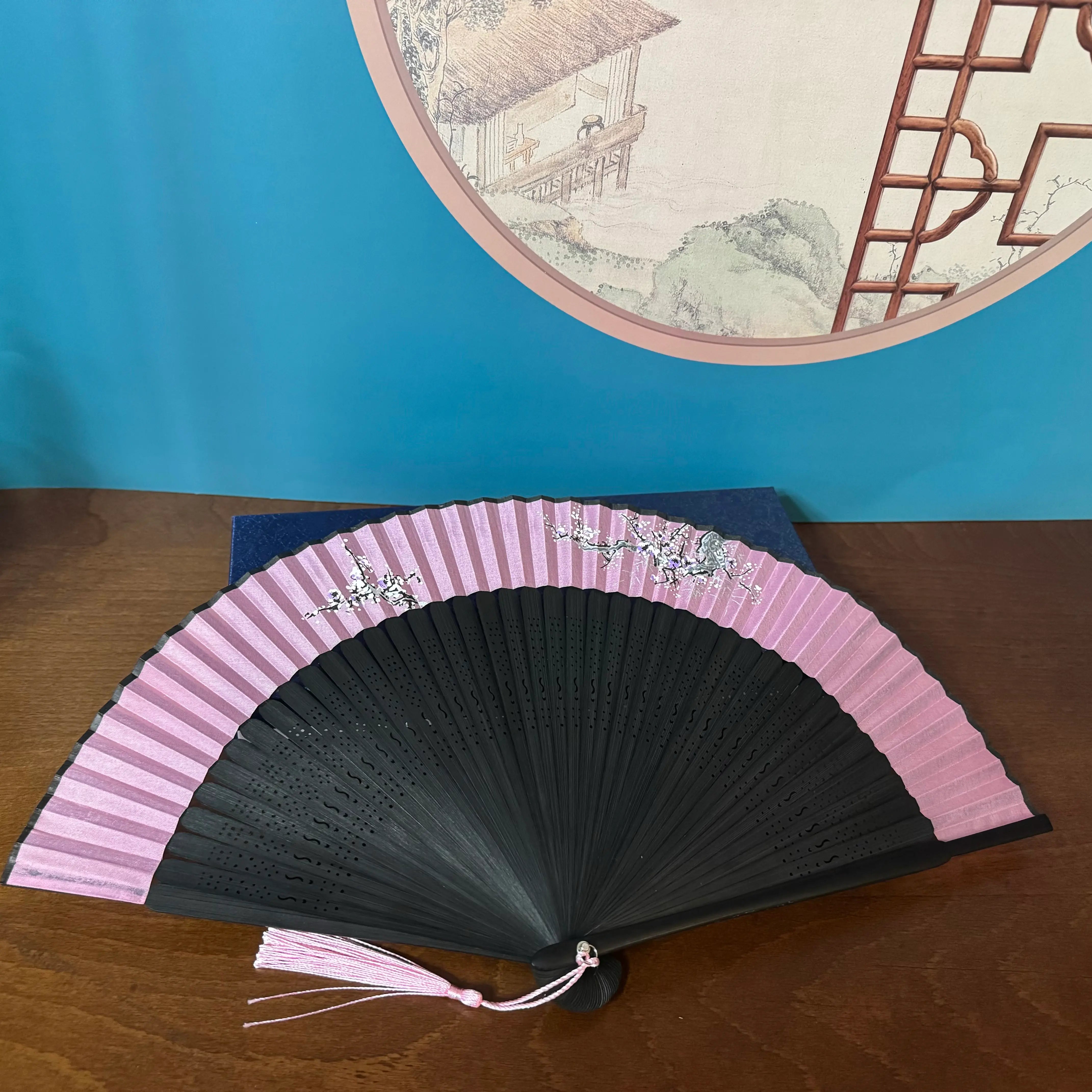 a plum blossom fan is placed on a dark blue box with surface patterns