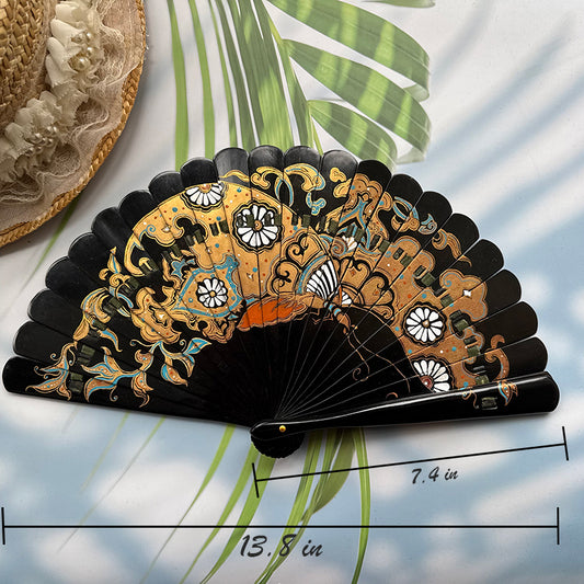 A Chinese lacquer folding fan with a gold-sprinkled pattern is placed on a table with sunlight, palm leaves and a straw hat in the background, with the size number indicated in the picture.