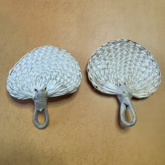 2 small size palm leaf fans on a surface