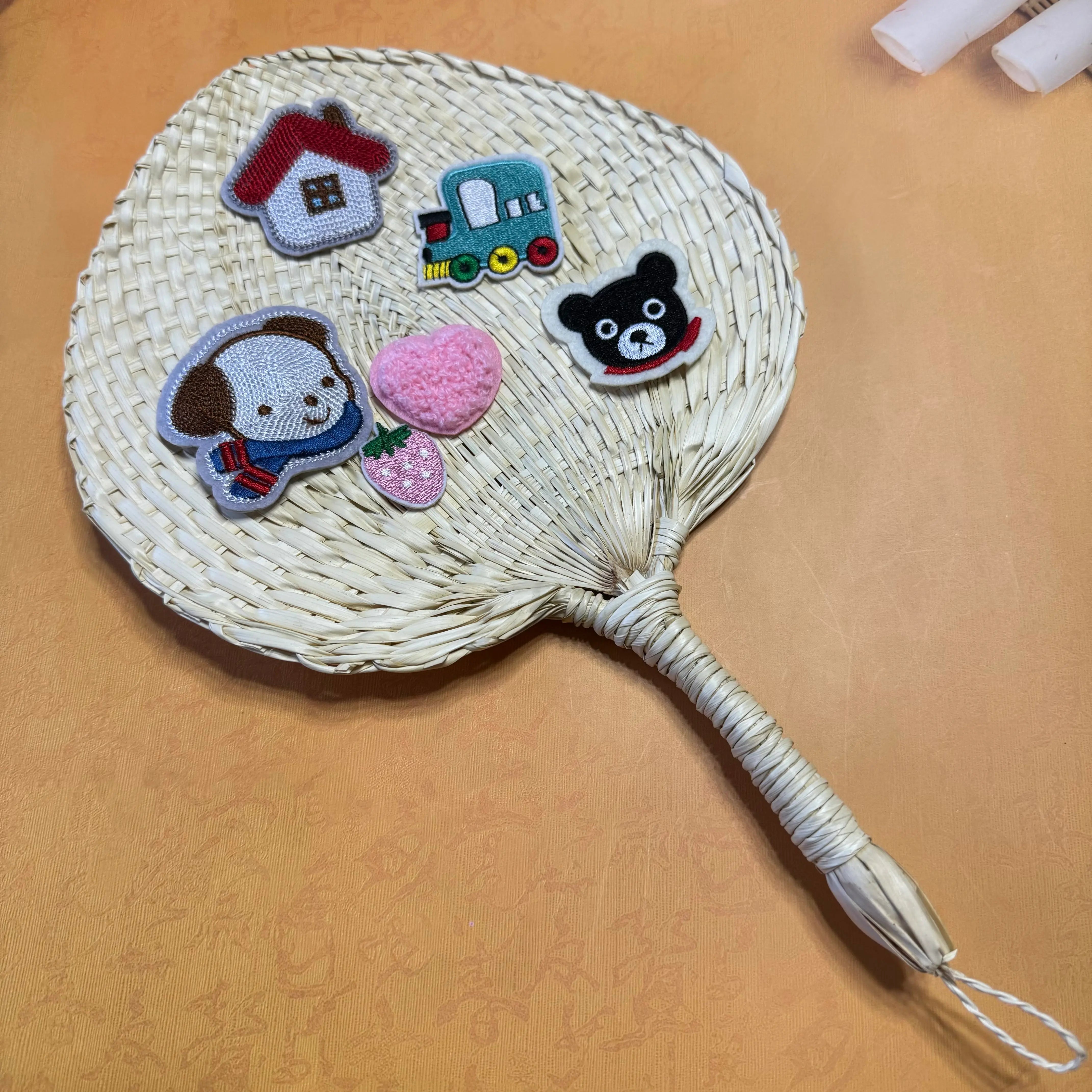 A palm leaf fan on a table, some stickers are on top of the fan