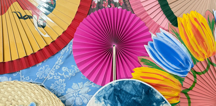 A lot of fans putting on a platform, there are Spanish fans, round folding fans and Japanese uchiwa, and a palm leaf fan at the left corner.