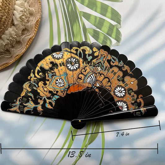 A Chinese lacquer folding fan with a gold-sprinkled pattern is placed on a table with sunlight, palm leaves and a straw hat in the background, with the size number indicated in the picture.