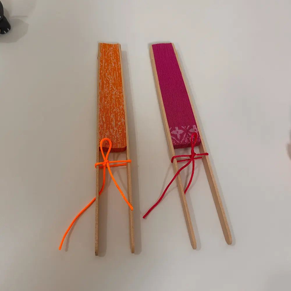 Two round folding fans are neatly secured in their folded position with a color-coordinated string.