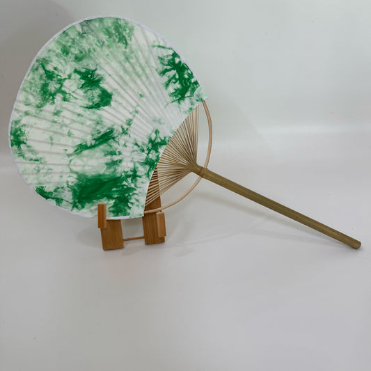 A Japanese round fan with ice flower green tie-dye print on the fan stand, with a white background.
