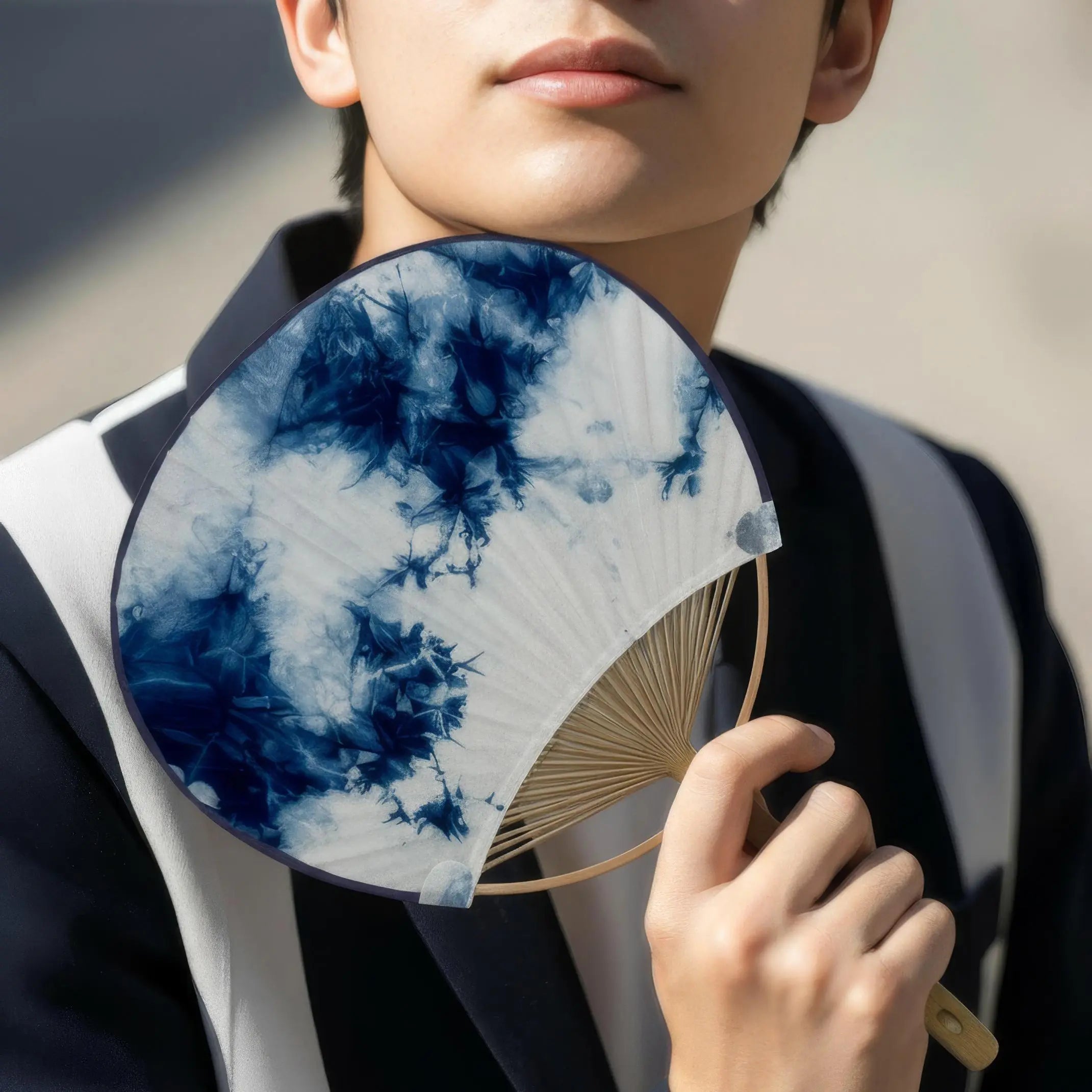 Uchiwa fan, a traditional Japanese round fan, held by an East Asian man.