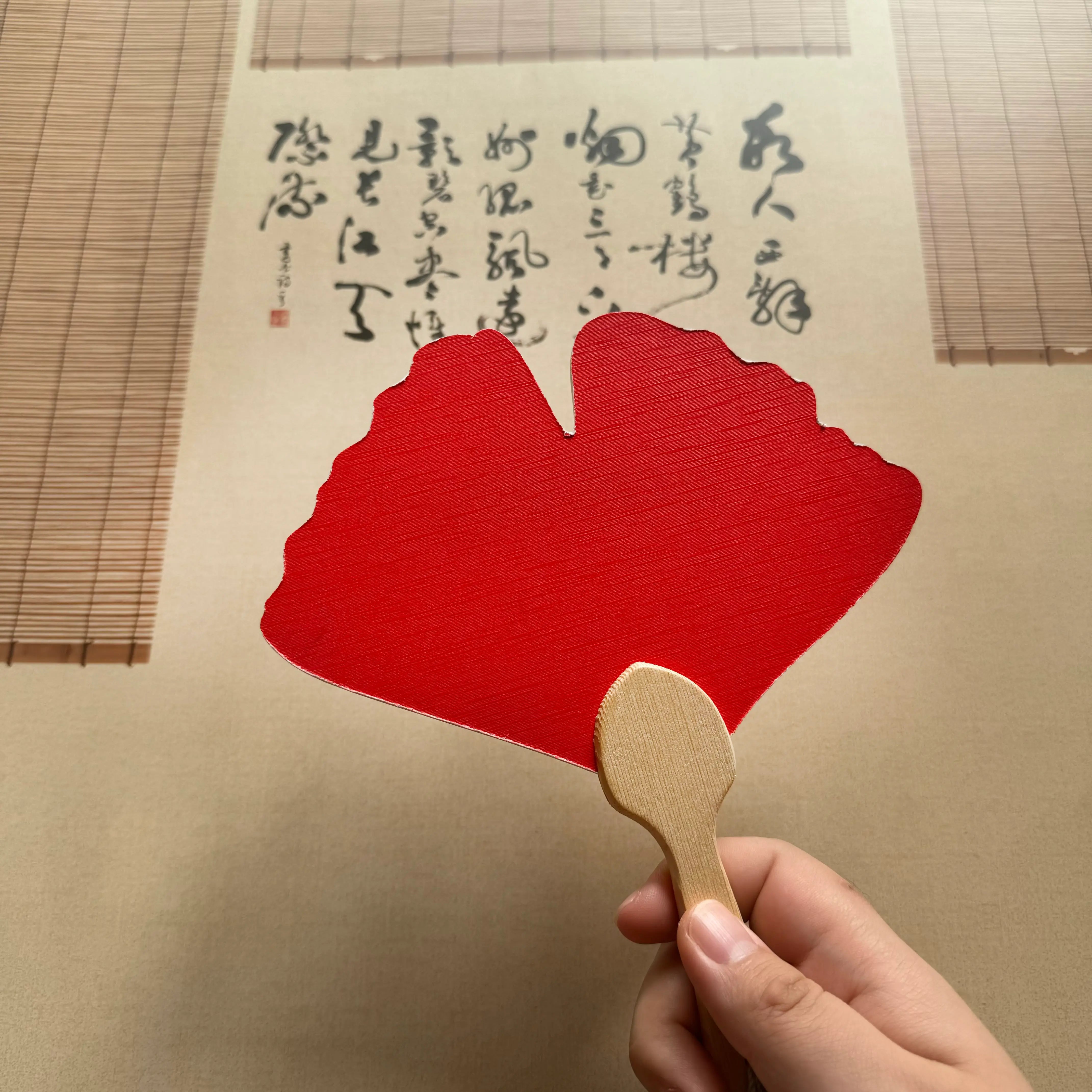 A ginkgo leaf shape fixed fan in front of a Chinese calligraphy
