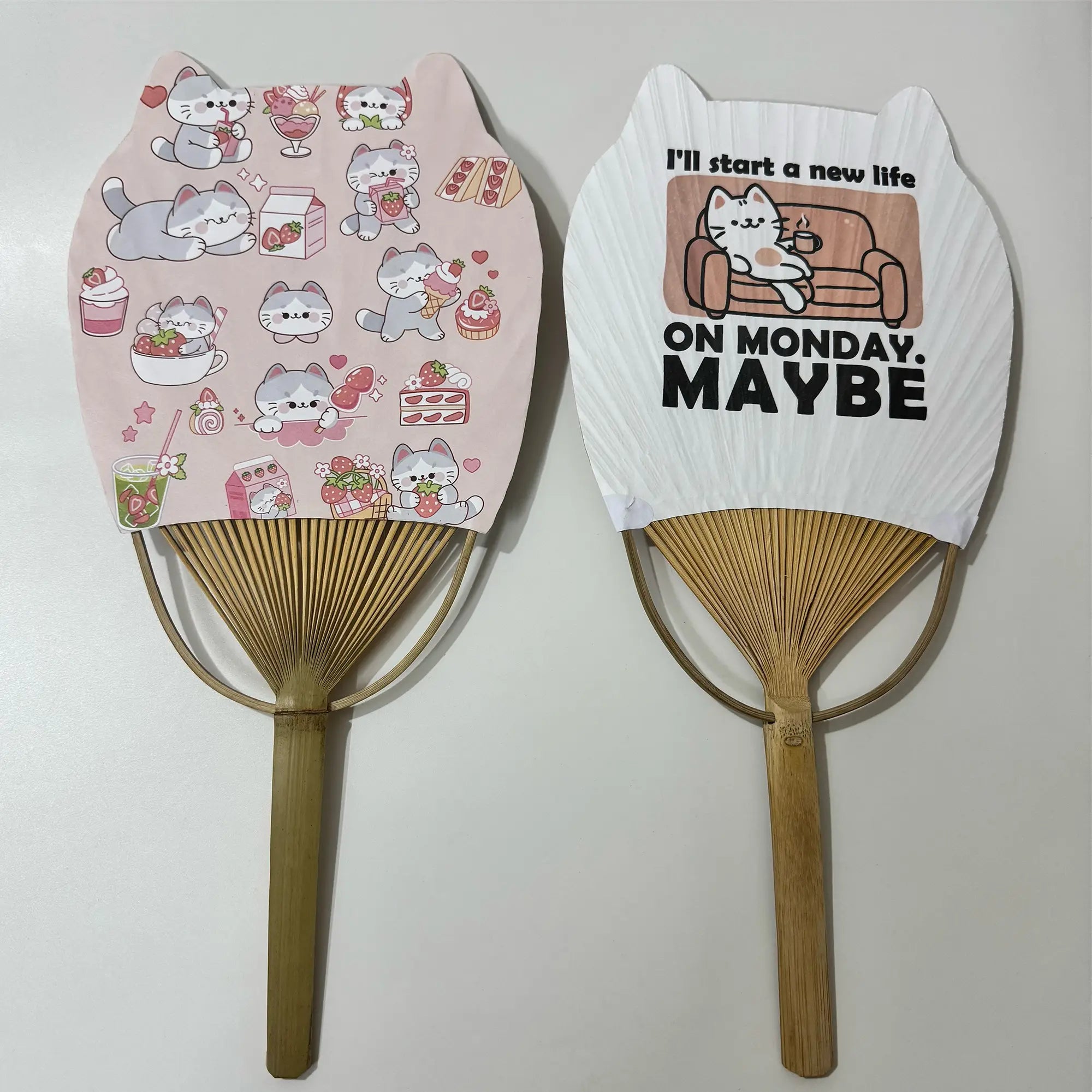 2 Japanese round fans (Uchiwa fans) with cat ears. On the fan panel it prints cat pictures and a cat meme "I'll start a new life on Monday. MAYBE". 