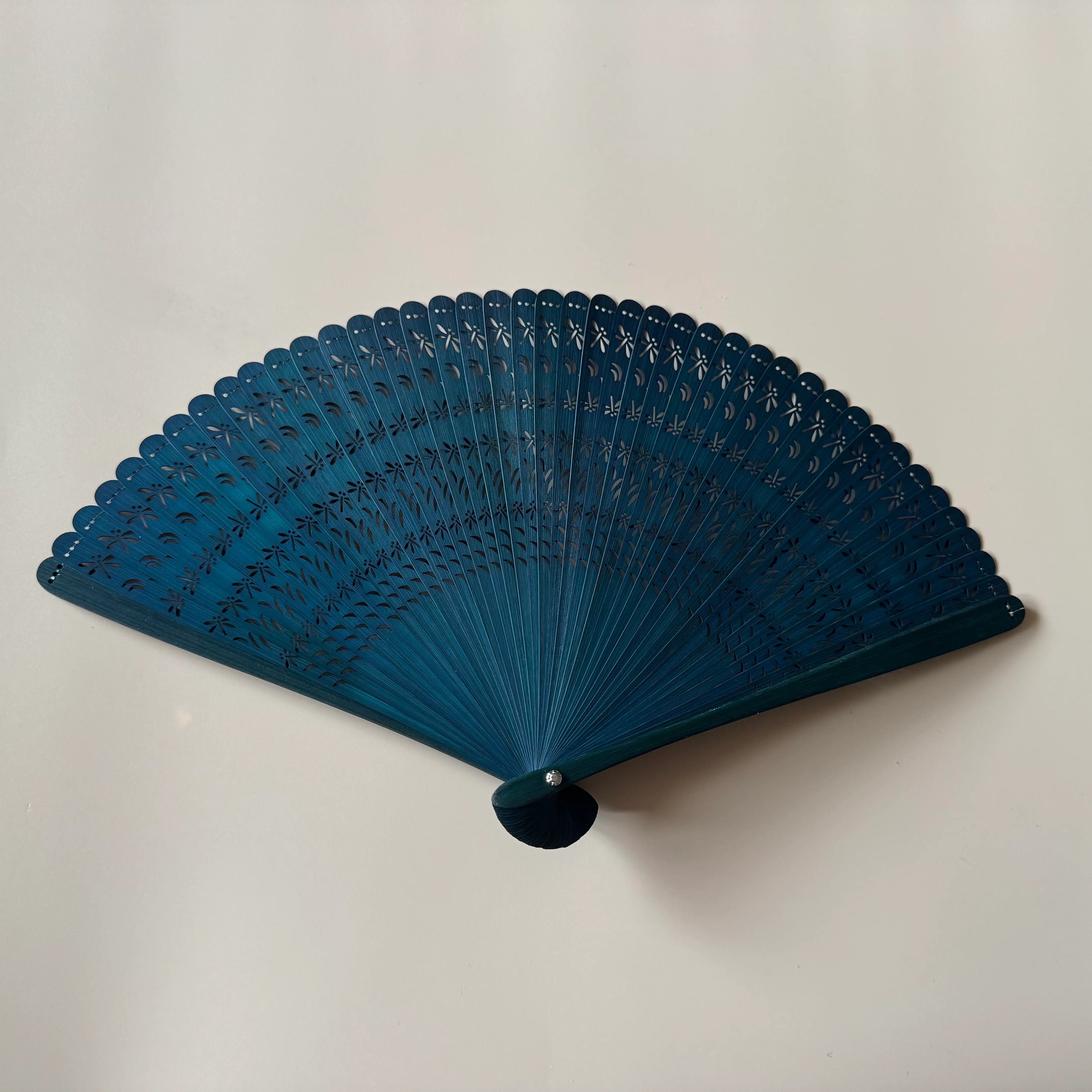 A green touqing bamboo fan on a white surface