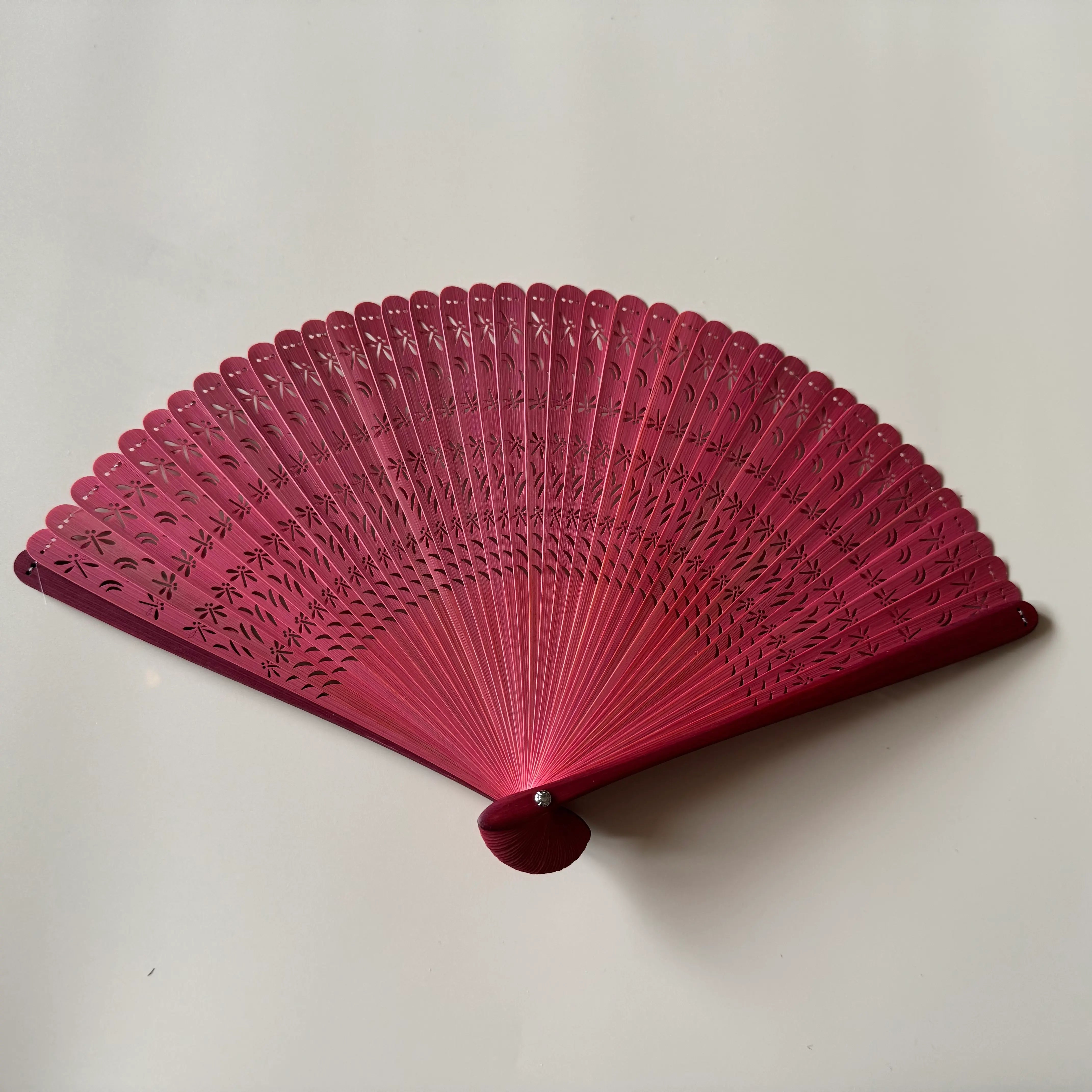 A red touqing bamboo fan on a white surface