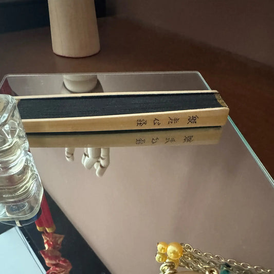 A folded Zen heart sutra fan placed on a mirror